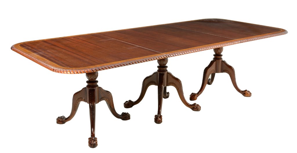 A CHIPPENDALE STYLE MAHOGANY DINING TABLE: A CHIPPENDALE STYLE MAHOGANY DINING TABLE The table having a banded rectangular top with rounded corners and a reeded border, raised on three tripod pedestal bases, each ending in claw and ball feet.