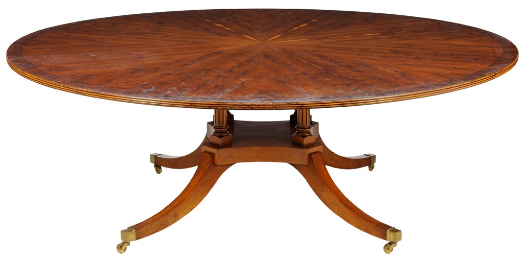 A REGENCY STYLE BURL WALNUT DINING TABLE: A REGENCY STYLE BURL WALNUT DINING TABLE The dining table having a circular top over a series of reeded supports, raised on splayed legs ending in caps and casters. H 29½ x W 83¾ x D 83¾ inches.