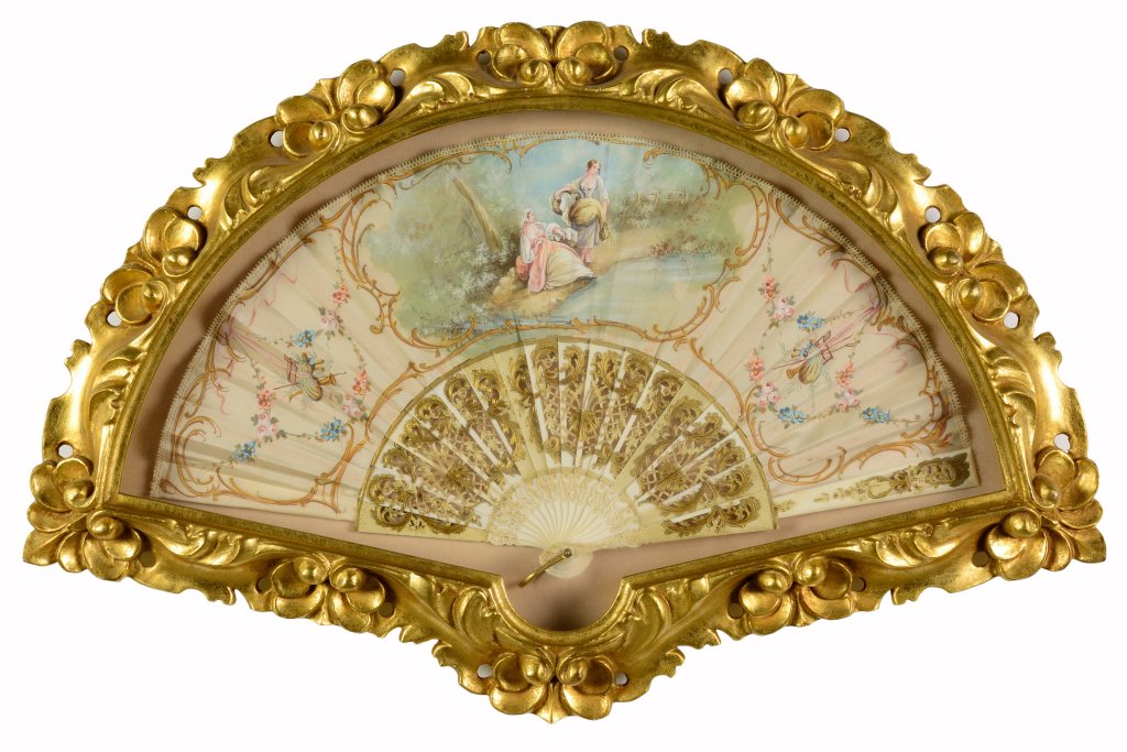 A LADY'S HAND PAINTED FAN WITH IVORY HANDLE IN A GILDED: A LADY'S HAND PAINTED FAN WITH IVORY HANDLE IN A GILDED SHADOW BOX FRAME The hand-painted fan on silk centering a Rococo pastoral scene medallion and flanked to each side by painted floral swags and d