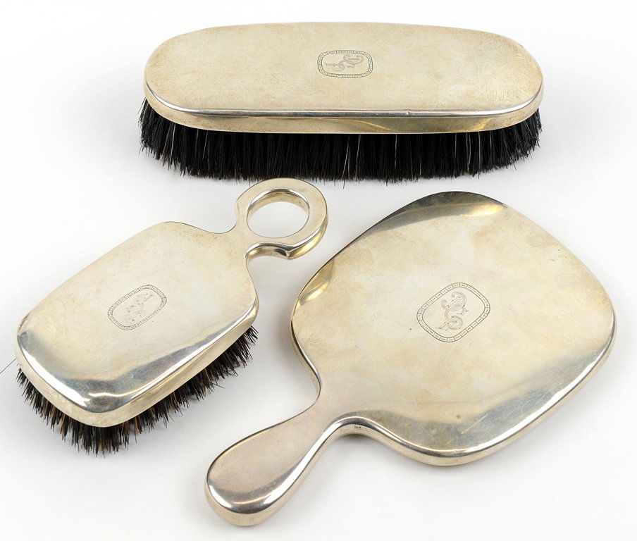 A THREE-PIECE LA PIERRE STERLING SILVER VANITY SET: A THREE-PIECE LA PIERRE STERLING SILVER VANITY SET Circa Early 20th Century The three-piece sterling silver hollowware vanity set comprising hand mirror and two brushes, each bearing monogram DCP. H 8