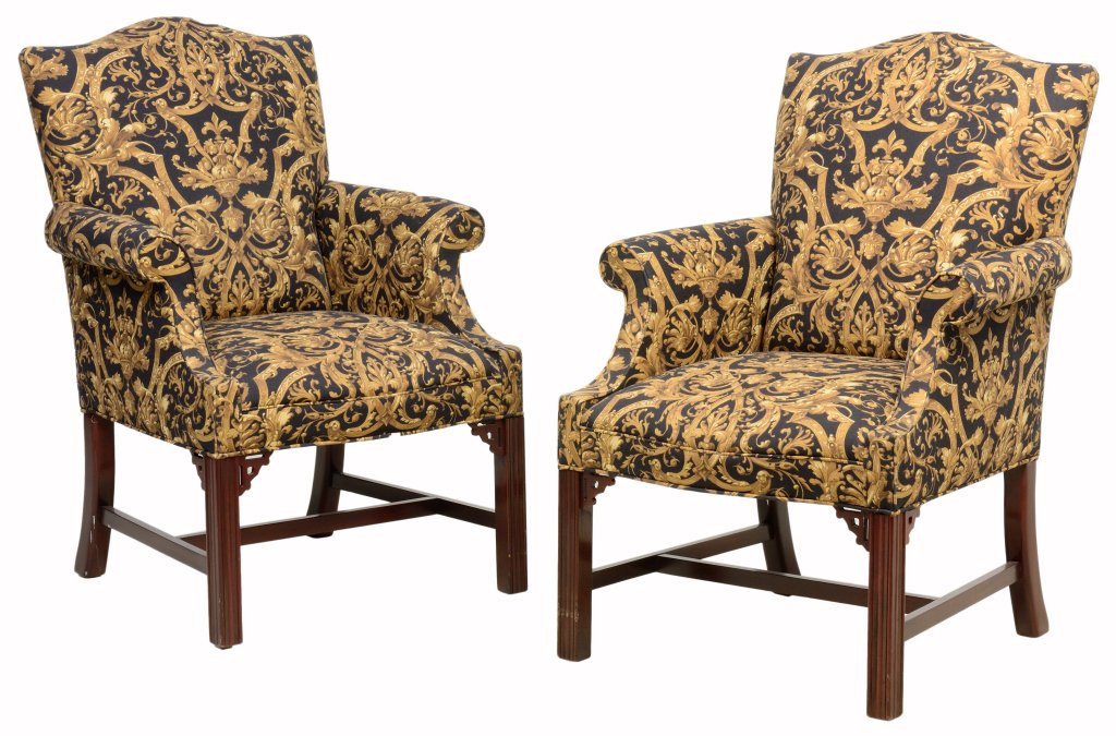 A PAIR OF CHIPPENDALE STYLE UPHOLSTERED ARMCHAIRS: A PAIR OF CHIPPENDALE STYLE UPHOLSTERED ARMCHAIRS The pair of armchairs having a domed crest rail over the upholstered back, arms and seat, raised on square fore legs with corner fretwork, joined by H