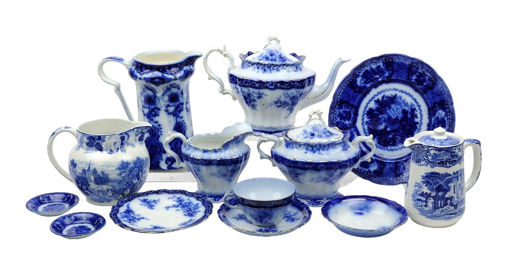 AN ASSEMBLED GROUP OF FLOW BLUE PORCELAIN ARTICLES 22: AN ASSEMBLED GROUP OF FLOW BLUE PORCELAIN ARTICLES The group comprising a tea set, a tall pitcher, and assorted dishes. 22 pieces total H 8¼ x W 8 x D 5½ inches.