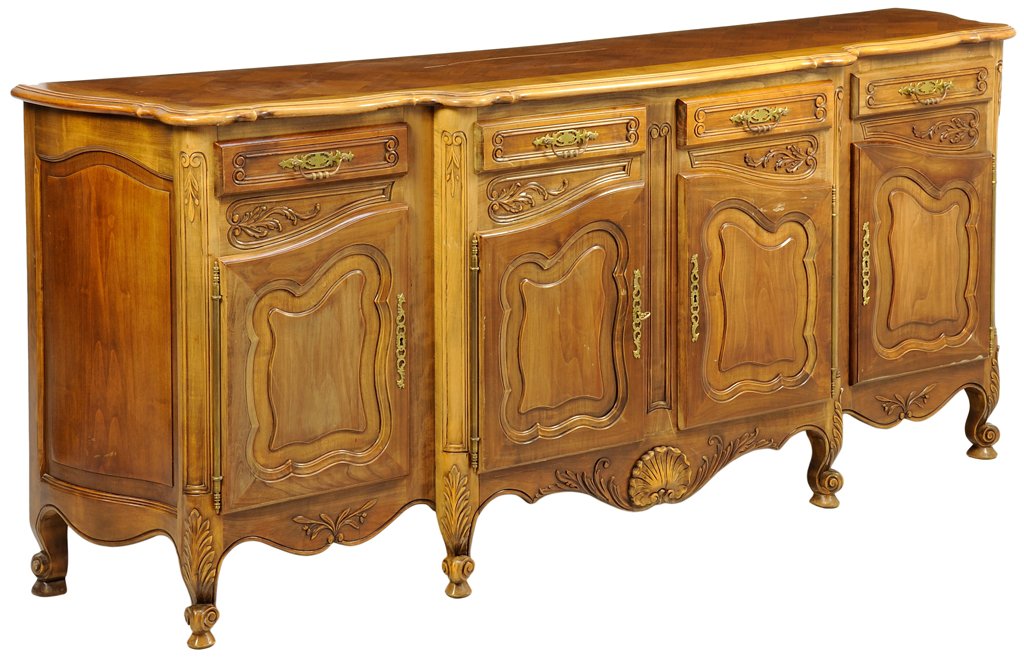 A FRENCH PROVINCIAL STYLE WALNUT SIDEBOARD: A FRENCH PROVINCIAL STYLE WALNUT SIDEBOARD The sideboard having a shaped rectangular top over four short drawers and four paneled door, coffer paneled sides, above the serpentine apron centered with a
