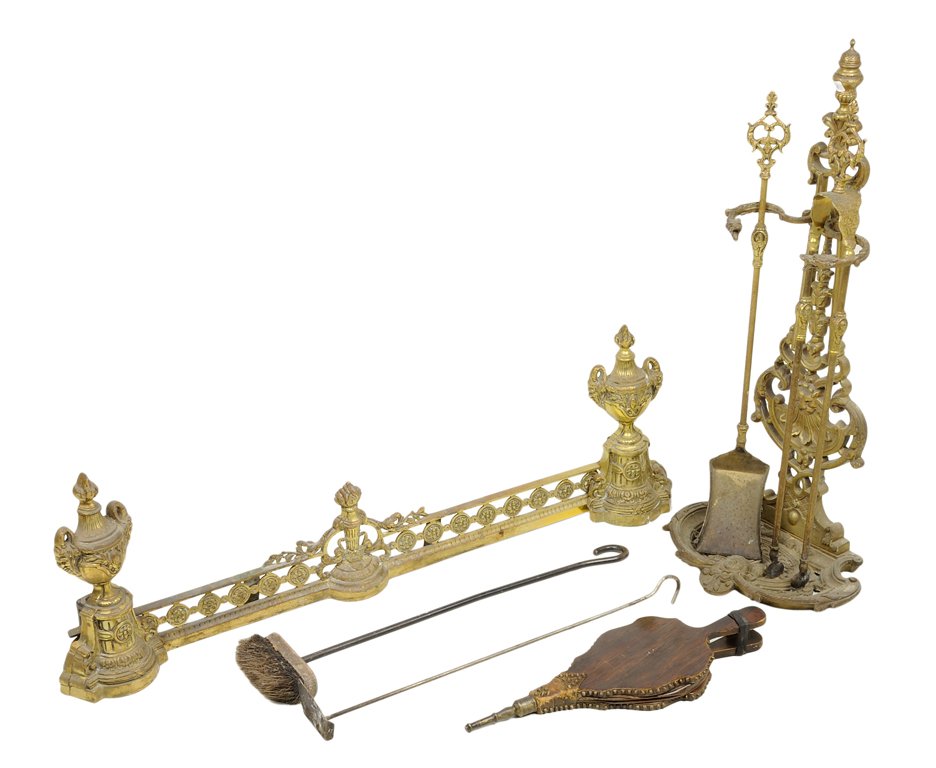 A GILT METAL FIREPLACE FENDER AND TOOL SET 7 pieces: A GILT METAL FIREPLACE FENDER AND TOOL SET Comprising a five-piece set of fireplace tools with accompanying stand and a fireplace fender terminating in dual urn-form supports. 7 pieces total H 28¼ x 