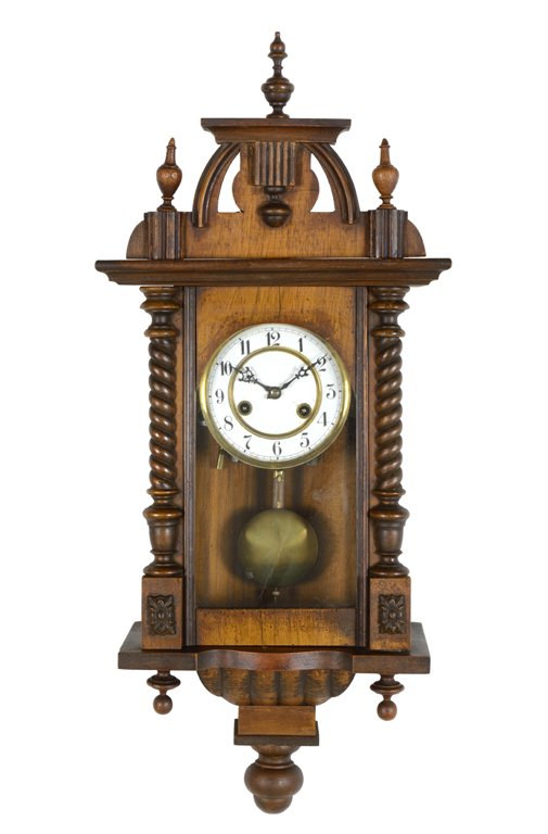 A FRENCH WALNUT WALL CLOCK: A FRENCH WALNUT WALL CLOCK The wall clock having an arched crest above the rectilinear pediment surmounted by finials, the circular enameled dial with Arabic hours over the pendulum, flanked by barley