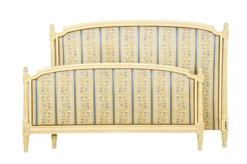 A FRENCH LOUIS XVI STYLE PAINTED AND UPHOLSTERED BED: A FRENCH LOUIS XVI STYLE PAINTED AND UPHOLSTERED BED The bed having a curved top rail, flanked by acorn form finials, over the upholstered back panel with nailhead border, raised on tapering cylindric