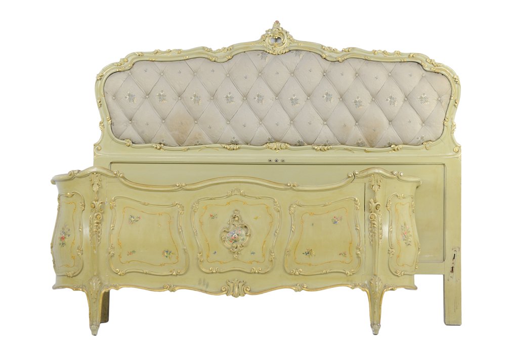 A VENETIAN STYLE PAINTED AND UPHOLSTERED BED: A VENETIAN STYLE PAINTED AND UPHOLSTERED BED The headboard having a carved foliate crest over the serpentine top rail over the button tufted upholstered back panel. The foot board having parcel gilt a
