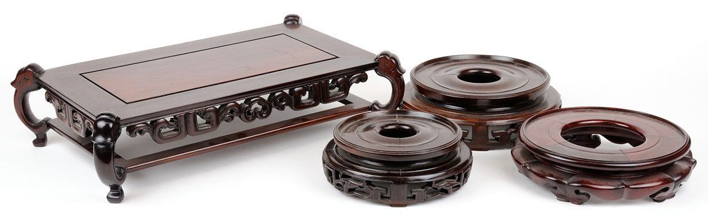 FOUR CHINESE CARVED HARDWOOD STANDS: FOUR CHINESE CARVED HARDWOOD STANDS Of varying form and size, comprising three assorted round carved wooden stands and one rectangular carved wooden stand raised on four scrolled feet. H 4¾ x W 18�