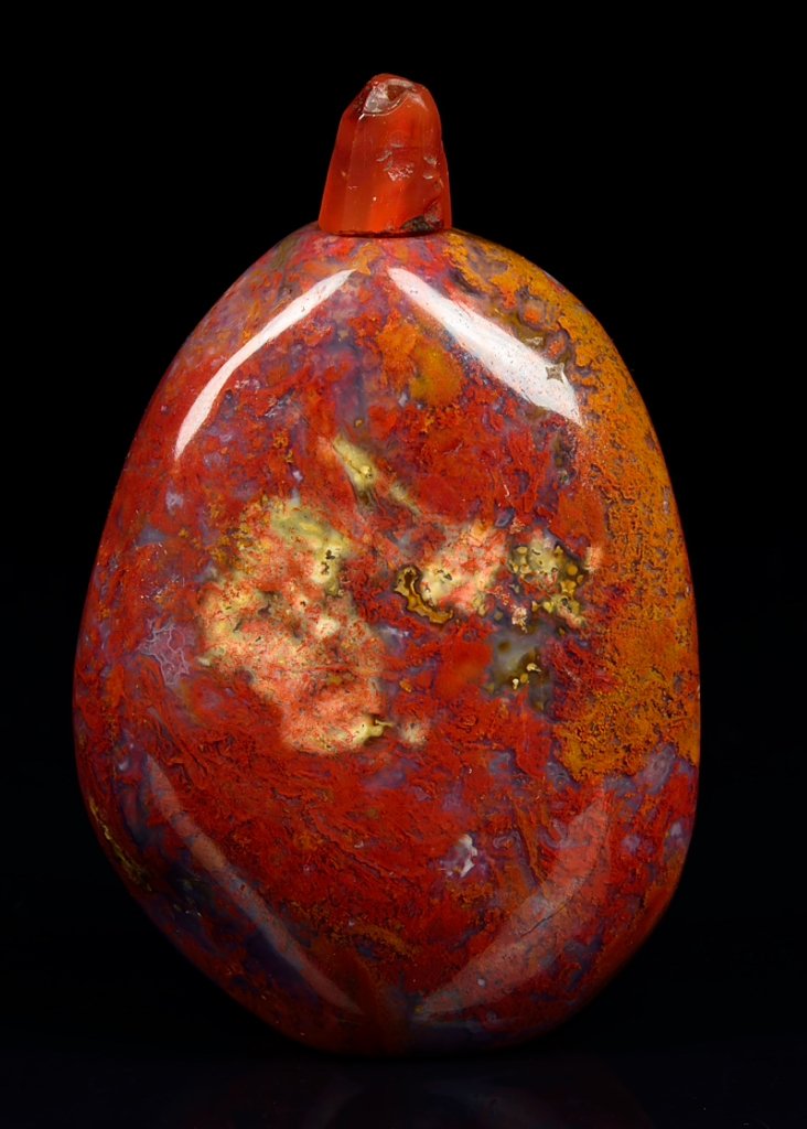 A CHINESE AGATE PEBBLE SNUFF BOTTLE: A CHINESE AGATE PEBBLE SNUFF BOTTLE The carved agate snuff bottle of natural pebble form, well hollowed, and surmounted by a carnelian stopper.