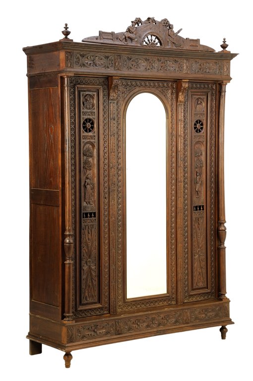 A FRENCH BRITTANY STYLE ARMOIRE: A FRENCH BRITTANY STYLE ARMOIRE The straight pediment surmounted by a demilune galleried crest flanked by peasant figures, atop a flared cornice terminating in turned finials, above the rosette carved