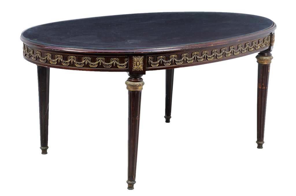 A FRENCH LOUIS XVI STYLE GILT METAL MOUNTED MAHOGANY: A FRENCH LOUIS XVI STYLE GILT METAL MOUNTED MAHOGANY DINING TABLE The dining table having an oval top, surmounted with a glass surface, above the gilt metal mounted apron, raised on square tapering le