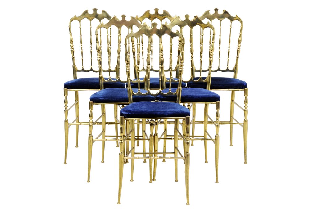 A SET OF SIX NEOCLASSICAL STYLE GILT METAL DINING: A SET OF SIX NEOCLASSICAL STYLE GILT METAL DINING CHAIRS Each chair having shaped crest rail over the vertical back splats, and upholstered trapezoidal seat, raised on cylindrical tapering legs, joine