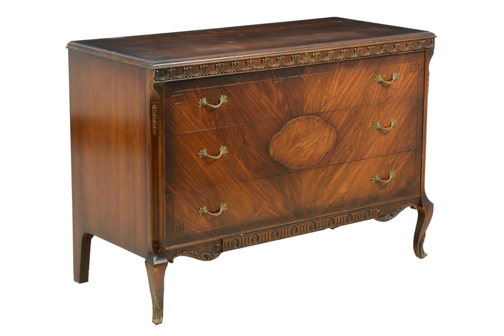 A FRENCH TRANSITIONAL STYLE CHEST OF DRAWERS: A FRENCH TRANSITIONAL STYLE CHEST OF DRAWERS The rectangular top over the rosette carved frieze, above three long drawers with bail handles, over the shaped apron, raised on cabriole fore legs. H 34½