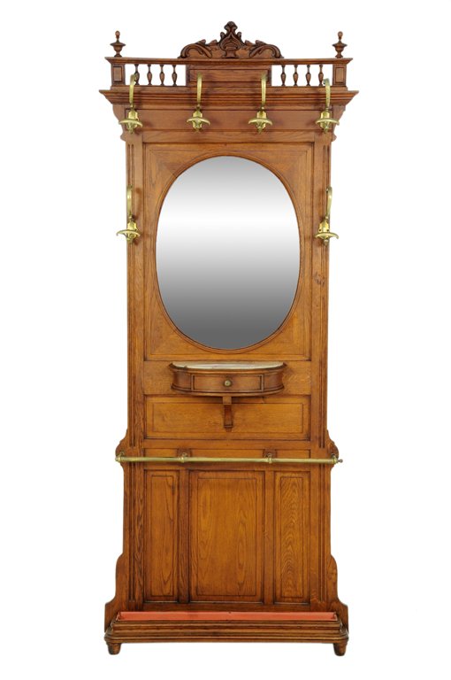 A RENAISSANCE REVIVAL HALL TREE: A RENAISSANCE REVIVAL HALL TREE The hall tree having a galleried cornice surmounted with a carved crest, over the back panel centered with an oval mirror plate, surrounded by a series of hooks, over a