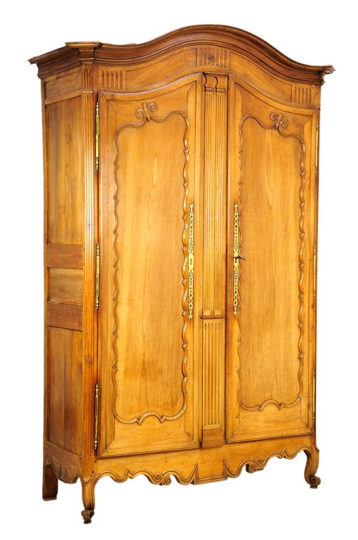 A FRENCH PROVINCIAL STYLE ARMOIRE: A FRENCH PROVINCIAL STYLE ARMOIRE The domed pediment and flared cornice over the gadroon carved frieze, atop two shaped paneled doors with scalloped border banding and vertical geometric openwork escu