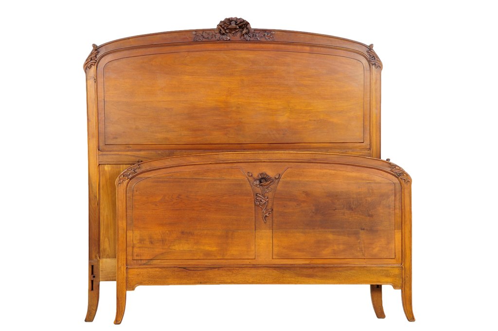 A FRENCH ART NOUVEAU STYLE BED: A FRENCH ART NOUVEAU STYLE BED The bed having a curved top rail centered with a carved foliate crest, raised on slightly splayed legs. Comprising headboard, footboard and side rails. W 57 inches.