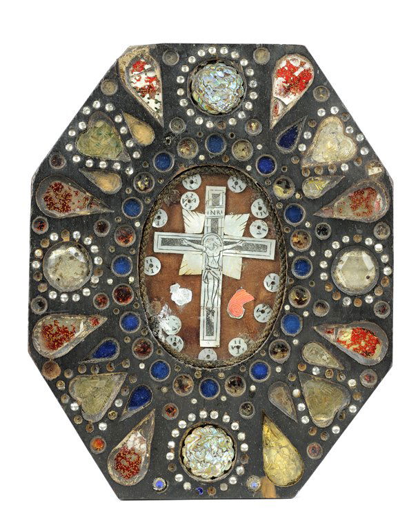 AN ANTIQUE MEXICAN DEVOTIONAL FOLK RETABLO OF THE: AN ANTIQUE MEXICAN DEVOTIONAL FOLK RETABLO OF THE CRUCIFIXION Of elongated octagonal form, the carved wooden frame centering a mother-of-pearl crucifix beneath glass. H 10¾ x W 8½ x D ½ inches.