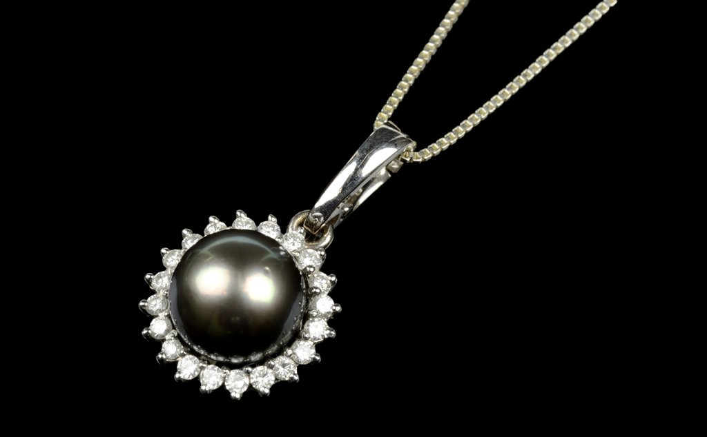 A BLACK TAHITIAN PEARL, DIAMOND AND 14 KARAT WHITE GOLD: A BLACK TAHITIAN PEARL, DIAMOND AND 14 KARAT WHITE GOLD PENDANT Centering a single black Tahitian pearl measuring approximately 10.2mm within a conforming prong-set diamond surround comprising twenty 