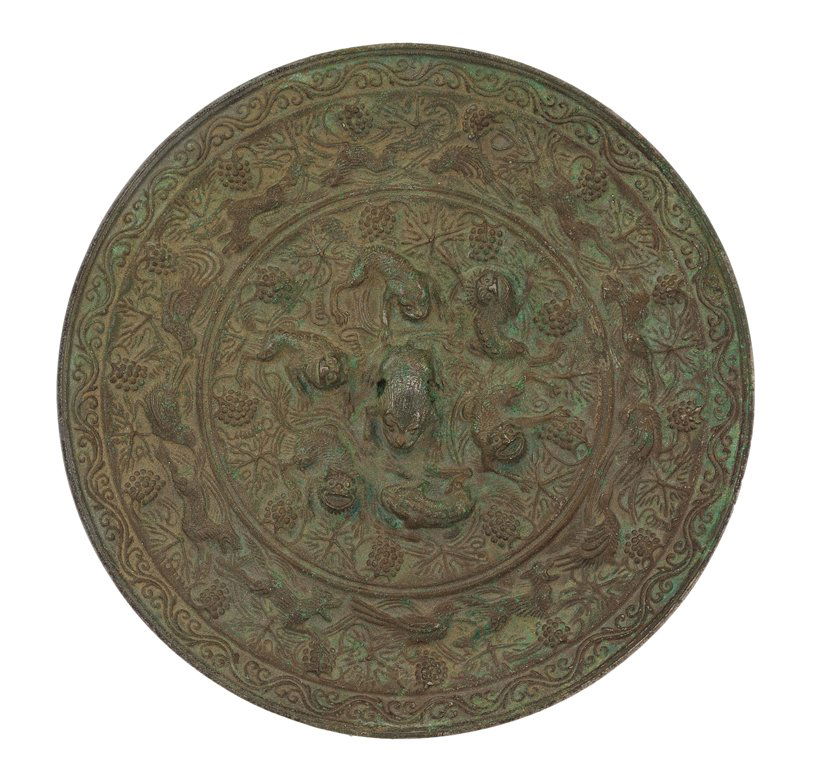 A CHINESE ARCHAIC FORM BRONZE MIRROR: A CHINESE ARCHAIC FORM BRONZE MIRROR In the Tang Dynasty style, centering a figural knob-form handle verso within a surround of similarly formed mythical beasts, having a repeating dragon and phoenix