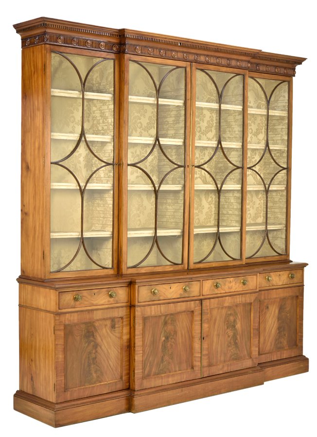 A GEORGE III STYLE MAHOGANY BREAKFRONT BOOKCASE: A GEORGE III STYLE MAHOGANY BREAKFRONT BOOKCASE 19th century The breakfront cabinet having a stepped molded cornice over the dentiled and rosette carved frieze, above four glazed doors opening to a sh