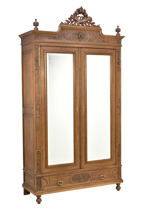 A FRENCH LOUIS XVI STYLE ARMOIRE: A FRENCH LOUIS XVI STYLE ARMOIRE The armoire having a stepped cornice surmounted with a pierce carved ribbon-tied wreath crest, flanked by finials, above the foliate carved frieze, fitted with two mir