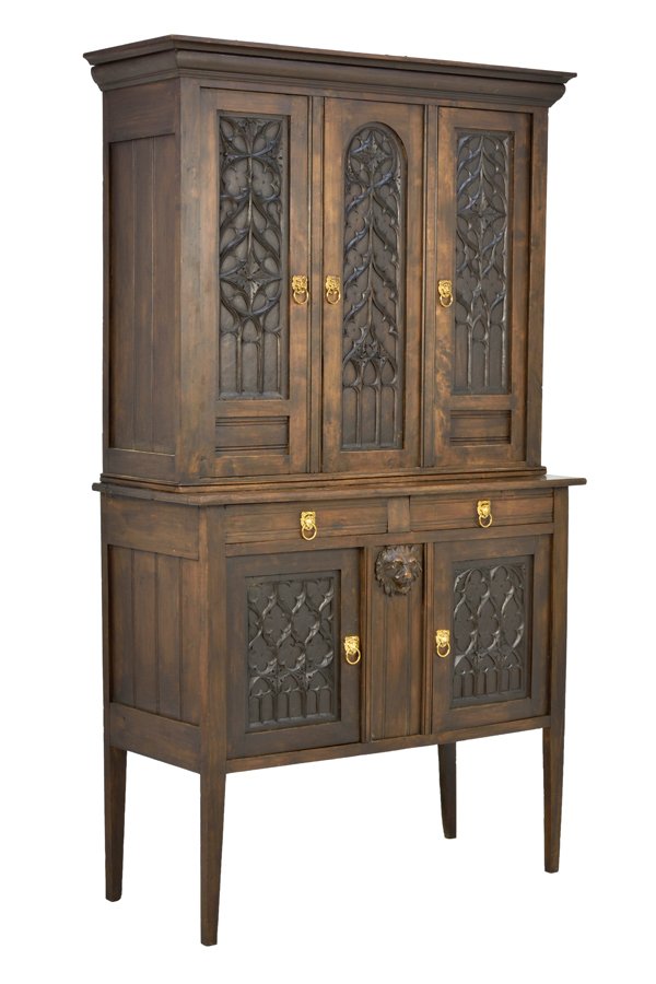 A GOTHIC REVIVAL SIDEBOARD CABINET: A GOTHIC REVIVAL SIDEBOARD CABINET The cabinet having a flared cornice over three paneled doors with carved tracery decoration, over the rectangular top and conforming case, fitted with two short draw