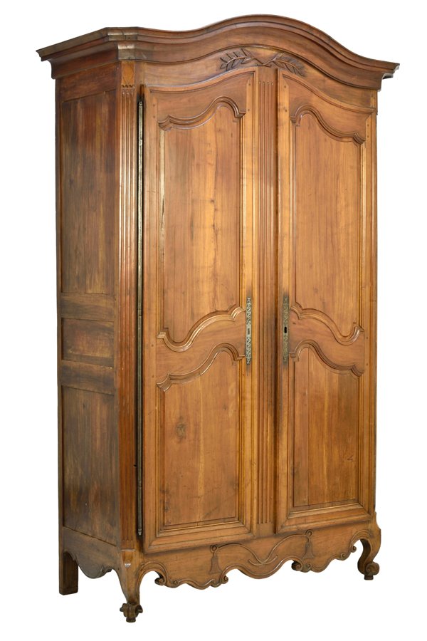 A FRENCH PROVINCIAL STYLE ARMOIRE: A FRENCH PROVINCIAL STYLE ARMOIRE The armoire having a domed cornice over the carved frieze, above the conforming case fitted with two paneled doors, over the serpentine apron, raised on scrolled fore