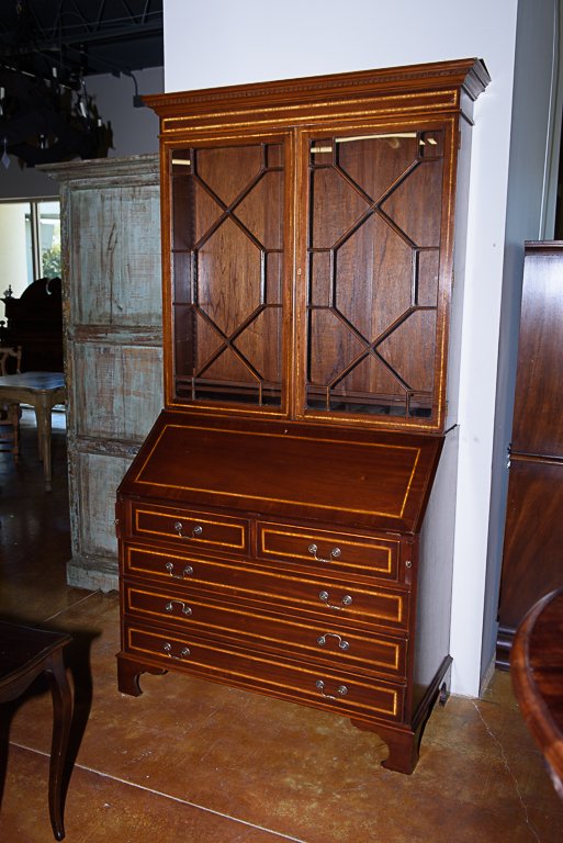 A CROSSBANDED MAHOGANY BUREAU SECRETARY: A CROSSBANDED MAHOGANY BUREAU SECRETARY The upper section with a molded cornice over two locking mullioned doors enclosing a two adjustable shelf interior, above a lower section with locking drop fron