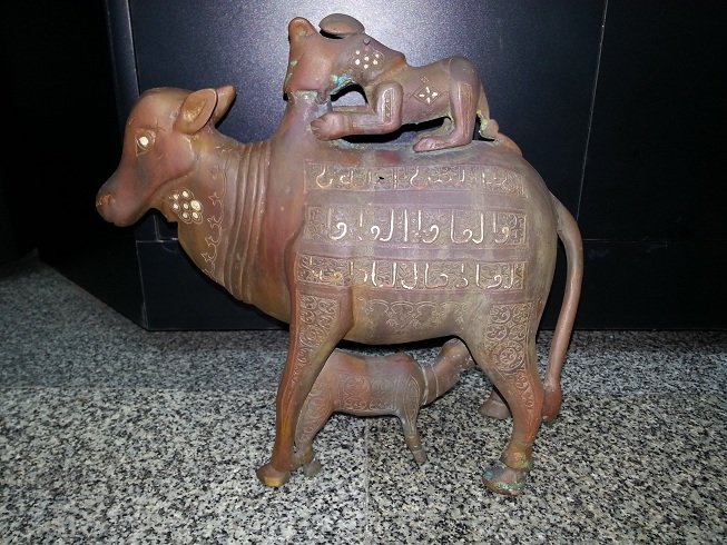 Islamic Style Silver inlaid Bronze Cow Cattle Lion @23: Beautiful Unique Islamic Style Bronze Silver inlaid Cow With Cattle And Lion on Top Attacks the Cow , all around is islamic writing silver inlaid . The Size is 9.5 " inches The Weight is 2.5 Kg.