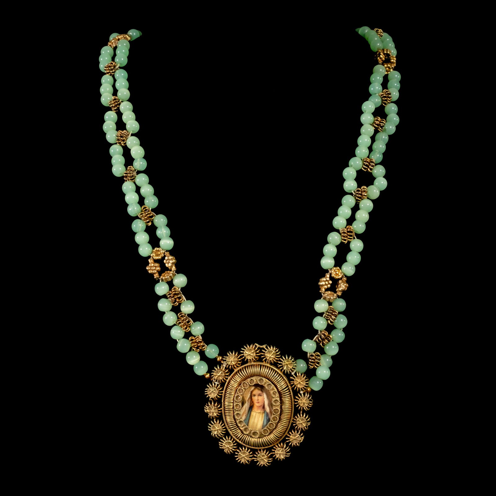 A Beaded Tamburin Necklace: Crafted in brass, the Tamburin necklaceshowcases green round beads. It features apendant depicting the Virgin Mary on the frontand St. Joseph with the Child Jesus on theback. Weighs 90.30 grams. The n
