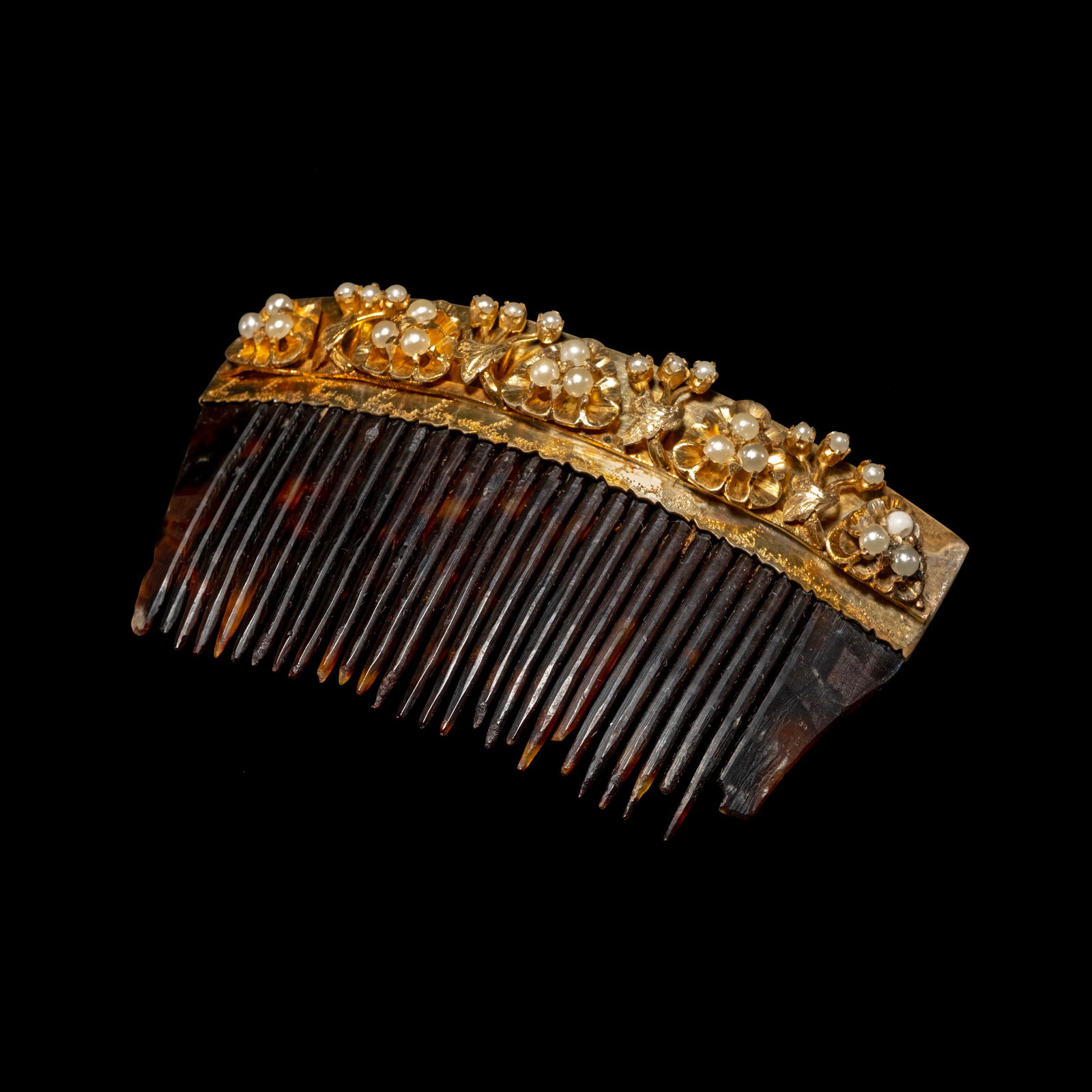 A Payneta Comb: The payneta comb crafted in silver and dippedin yellow gold features a delicate floral designaccented by seed pearls. Weighs 28.60 grams.