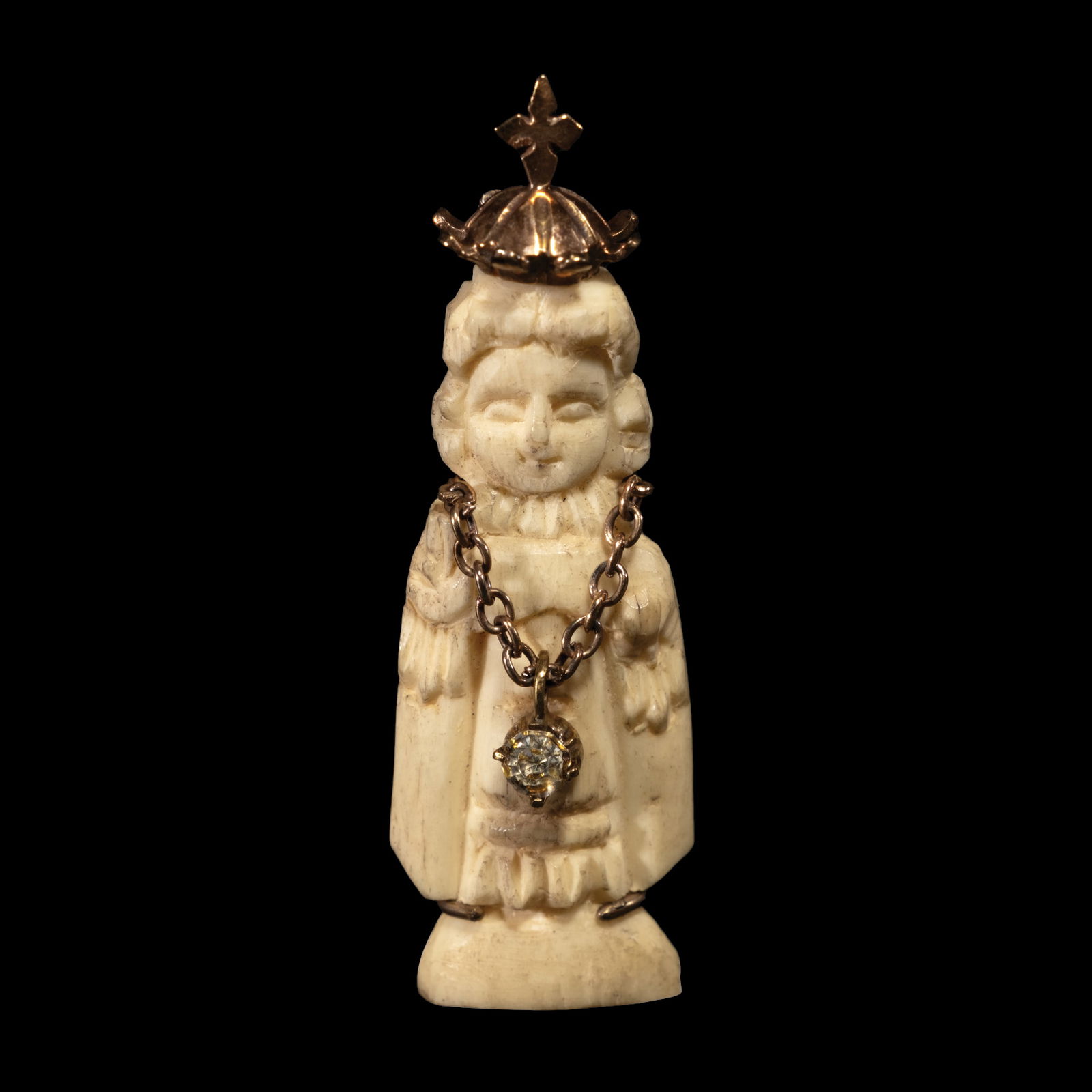 A Carved Santo Niño Pendant in Silver: The pendant features a carved image of SantoNino on bone set in a silver setting. Weighs 4.70 grams.