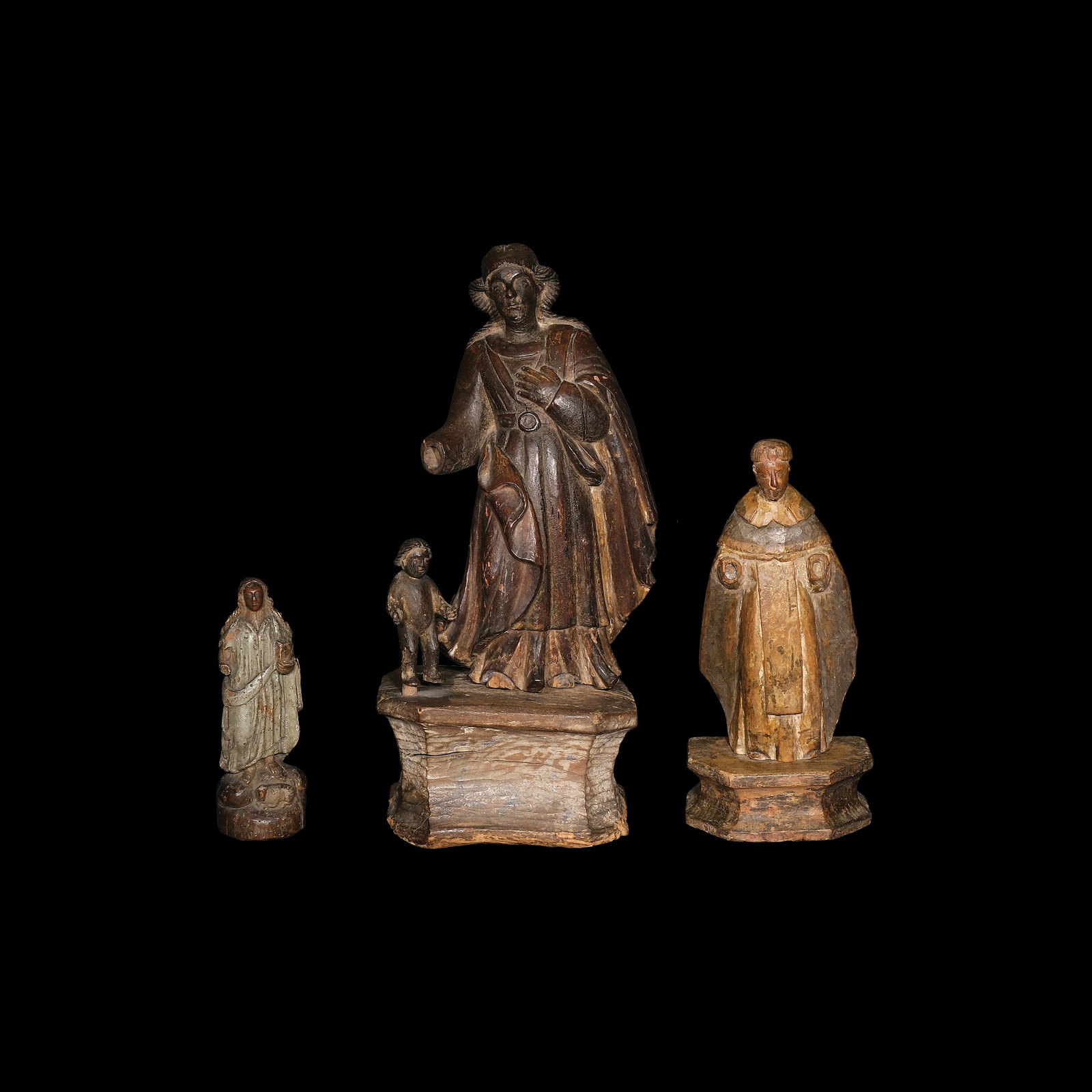 Three 19th Century Santos De Bulto: a.) H: 8 1/2” (22 cm) L: 3” (8 cm) W: 2 3/4” (7 cm) b.) H: 19” (48 cm) L: 8 3/4” (22 cm) W: 6 3/4” (17 cm) c.) H: 12 3/4” (32 cm) L: 6 1/4” (16 cm) W: 4
