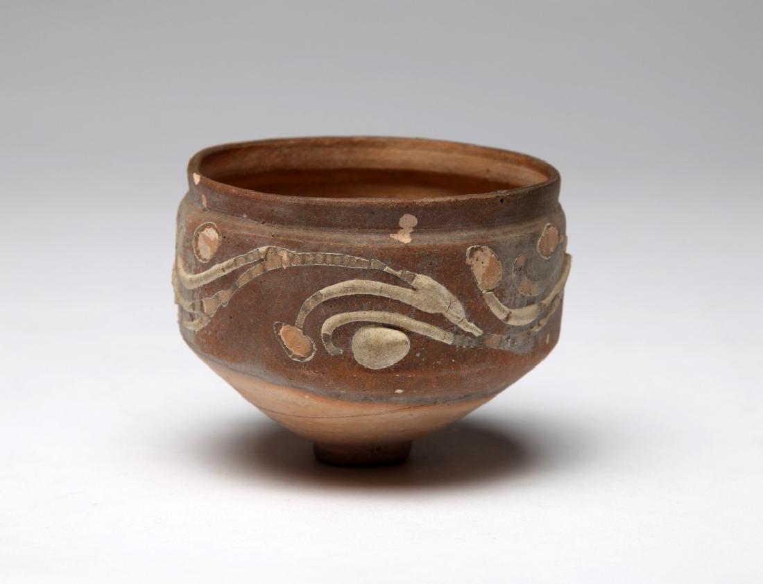 Gaulish Pottery Bowl: Western Europe; c. 4th century AD.From Germany or perhaps late Roman England, standing on a small foot and with applied white floral decorations. Rare! 3 1/2" (9 cm) Provenance: The John J. Slocum Col