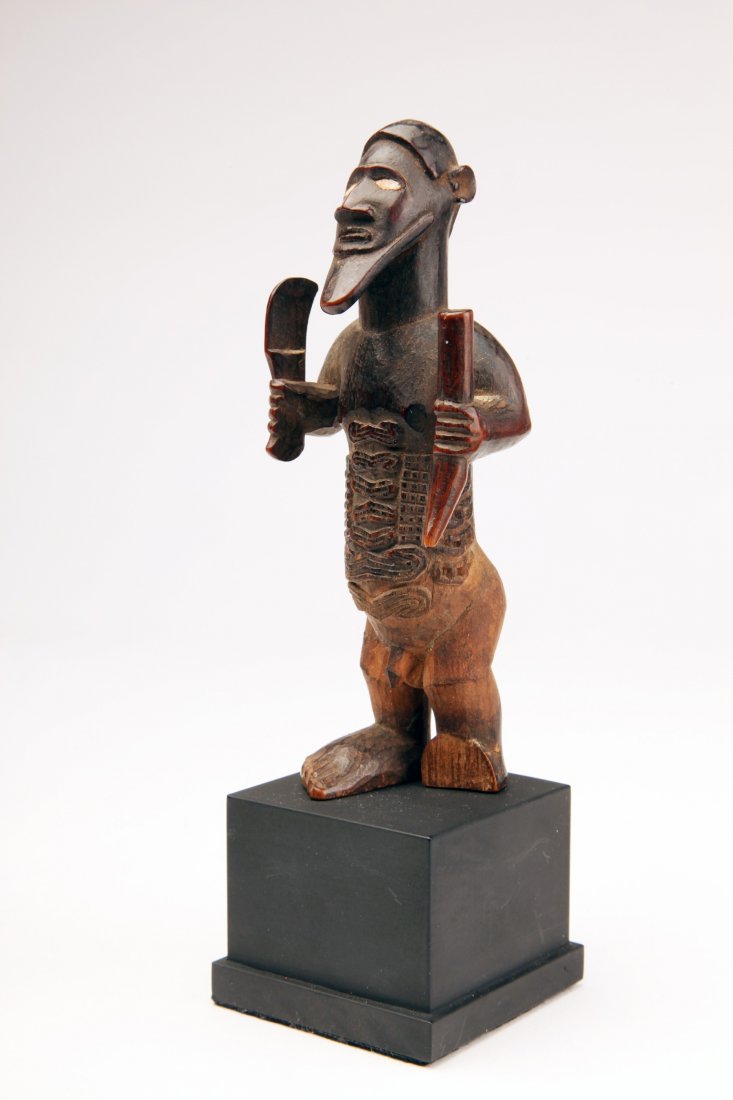 Rare African Bembe Male Figure: Congo; Antique. Fine and very old figure of a male with extensive scarification to torso, holding a horn and knife, his eyes inlaid with bone. Custom stand. Height without base; 5.25" (13.2 cm) Purcha