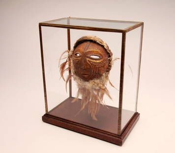 Rare African Mask: Congo; Antique. Mask carved from a cranium with feather attachments and cloth and hair at top. Deeply carved chevron pattern to cheeks. Custom glass display case. Very old French label to reverse side