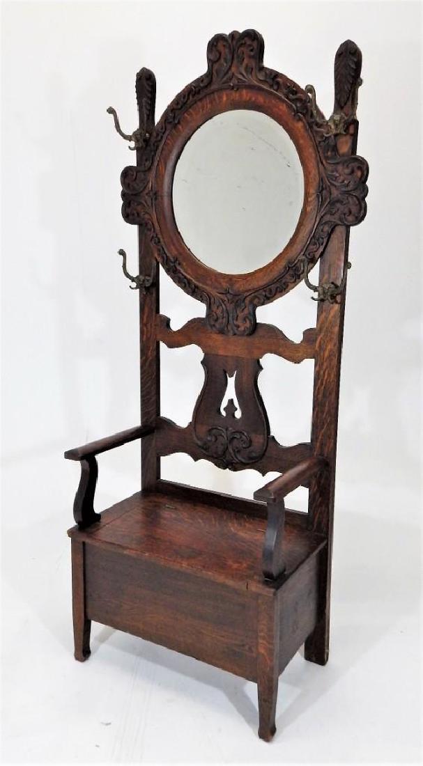 Antique Victorian Oak Hall Stand: Victorian oak hall stand, ornately carved around mirror, gorgoyle brass hangers with lift top bench. Width: 31" Length: 17" Height: 78" Circa: 1900, very good original condition