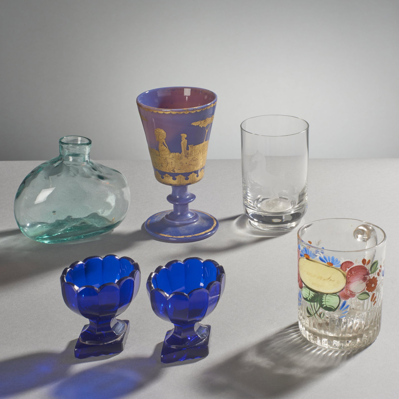 Group Of Antique Glass Items: 19th century fine group of assorted glass consisting of cobalt open salts quilted flask opaque purple goblet with gilt courting scene remember me mug and etched tumbler with internal large silver coin