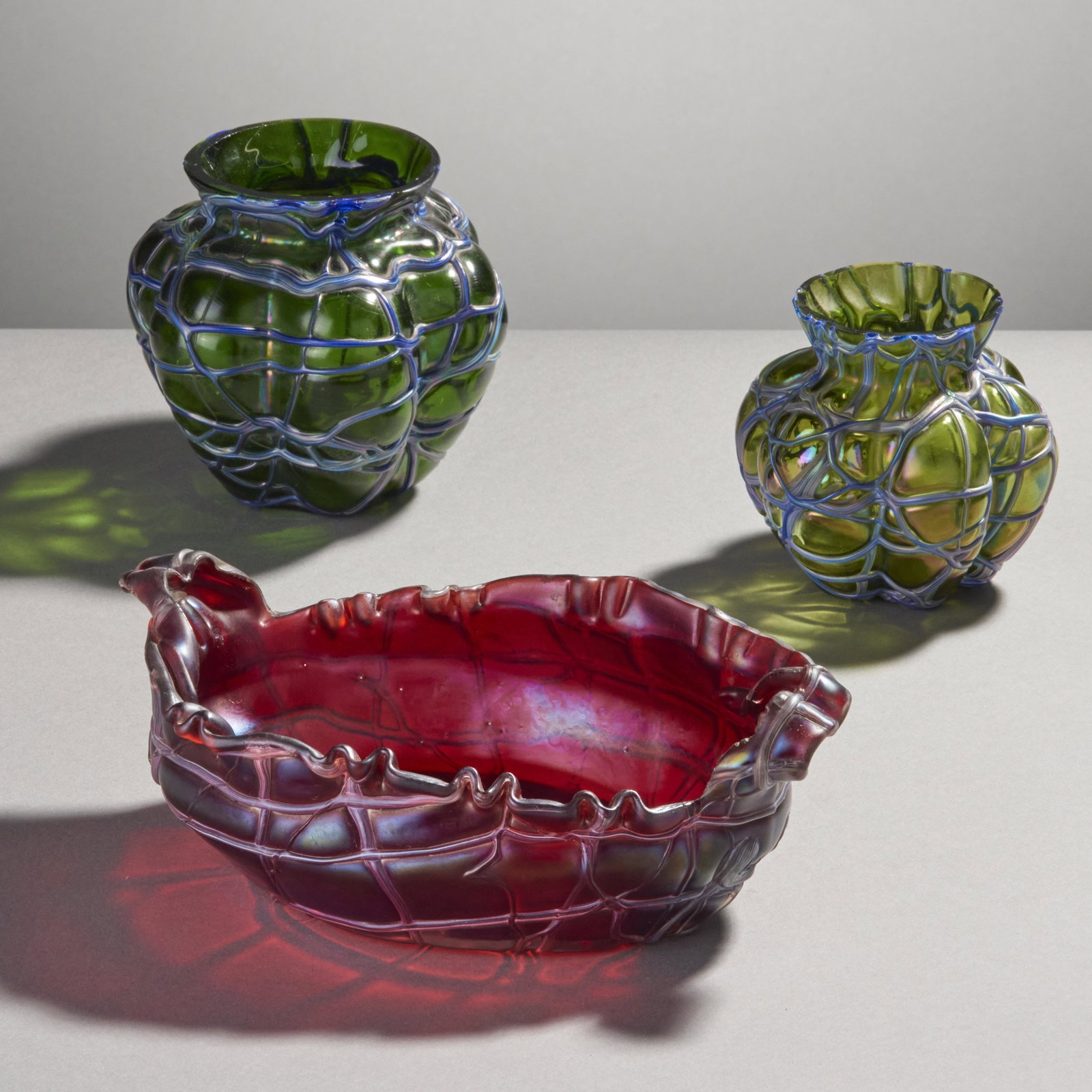 Loetz Type Art Glass Objects, Lot Of 3: Lot of 3 possibly Loetz (Kralik) art glass objects including 2 green lobed vases with applied draped glass overlay and 1 red glass serving dish with free-form handles and applied draped glass overlay.