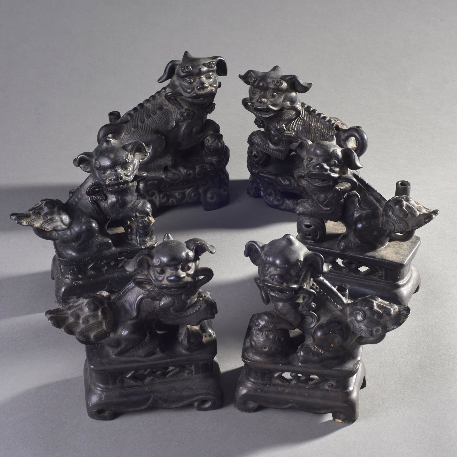 Group Of 3 Pairs Of Chinese Earthenware Foo Dog: Group of 3 pairs of Chinese earthenware Foo dog guardian figures with black glaze sitting atop adjoined decorative bases. Condition: minor losses. Measures: 8" height tallest