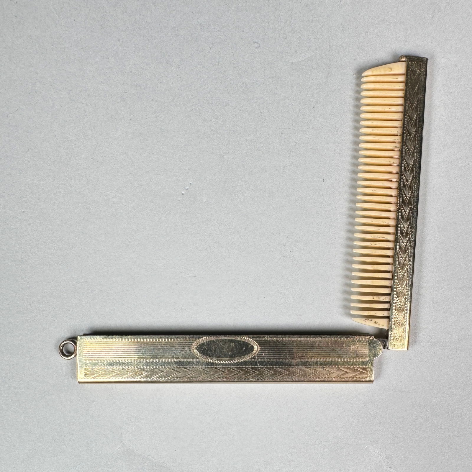 Vintage Gold-Tone Folding Pocket Comb: 1920s vintage gold-tone folding pocket comb, featuring intricate engraving on the metal casing. Case: 2.75" long 14 grams