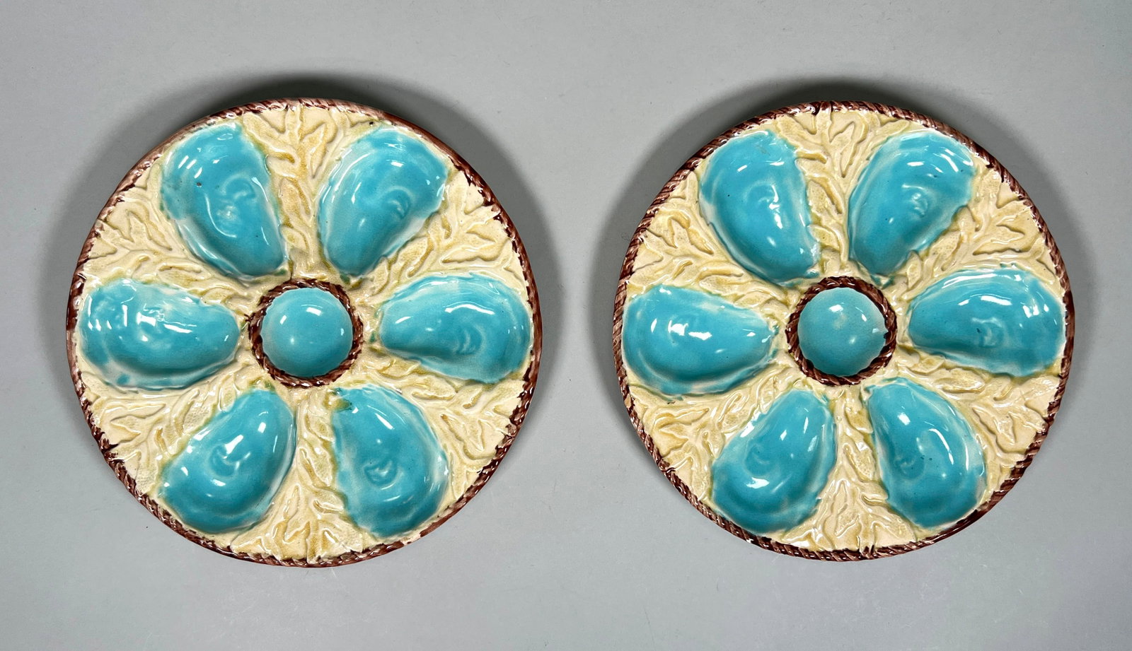 Pair of Fielding & Co. Majolica Oyster Plates: A pair of 19th century S. Fielding & Co. Majolica oyster plates, each featuring six compartments for oysters arranged in a floral pattern with a central well for sauce. Diameter: 9.25 in