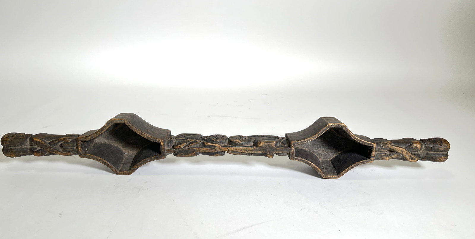 Hand-Carved Wooden 'Linnak' Drinking Vessel: A hand-carved wooden ceremonial drinking vessel, or "Linnak," from the Paiwan people of Tawain, featuring intricate carvings of stylized figures and floral motifs.