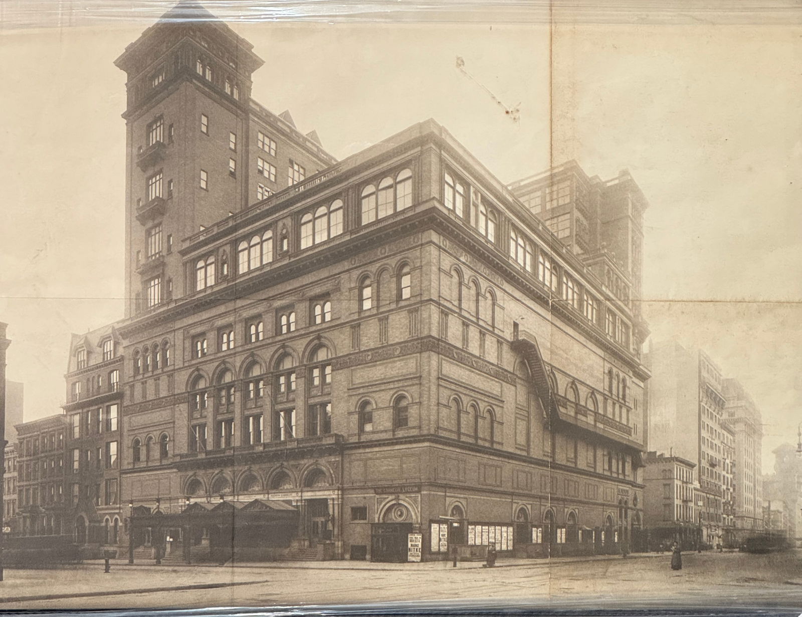 Vintage Poster of Carnegie Hall, New York City 1900s: A vintage print of Carnegie Hall in New York City, 1900s. The photograph captures the architectural grandeur of the building, highlighting its multiple floors, arched windows, and prominent corner tow