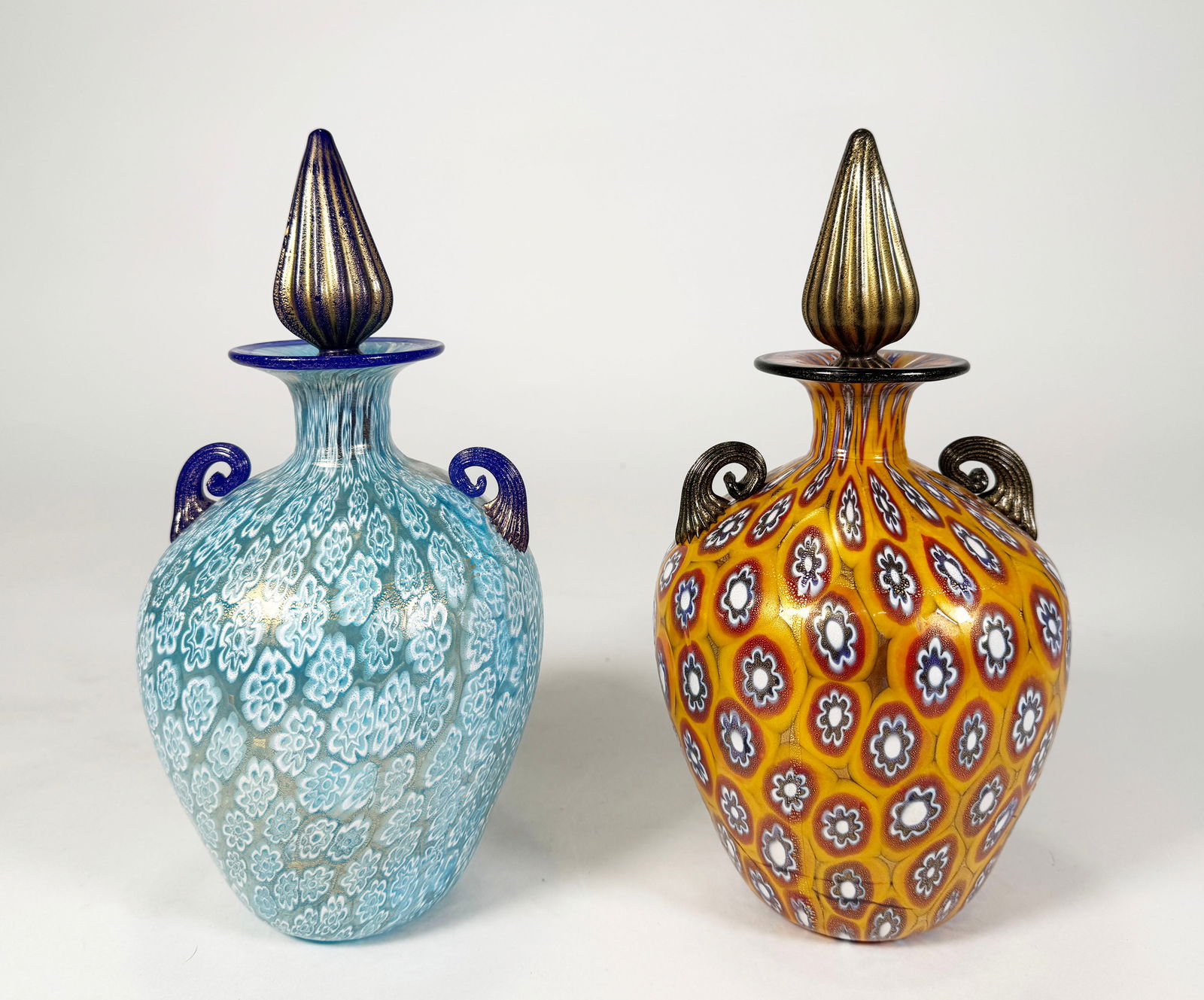 Gambaro & Poggi Murano Glass Decanters: Gambaro & Poggi Murano glass millefiori decanters, each with two handles and stoppers. Dimensions: Height with stopper: 9.75 inchesWeight: 70 oz