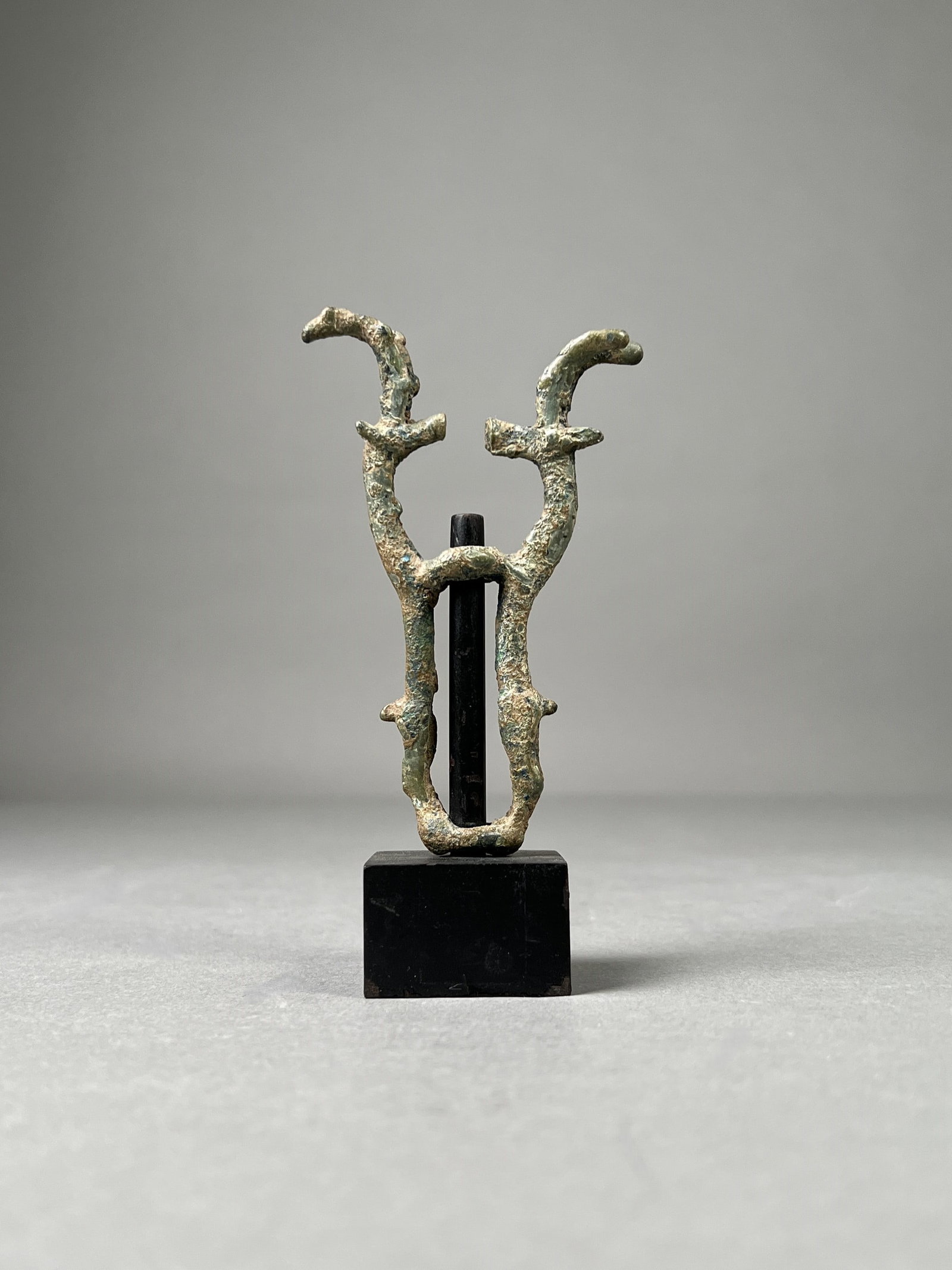 Luristan Bronze Finial with Stand: Luristan bronze finial depicting a pair of opposing animals with antlers on custom stand. Dimensions: Height: 5 in. Width: 1.5 in. Weight: 3.