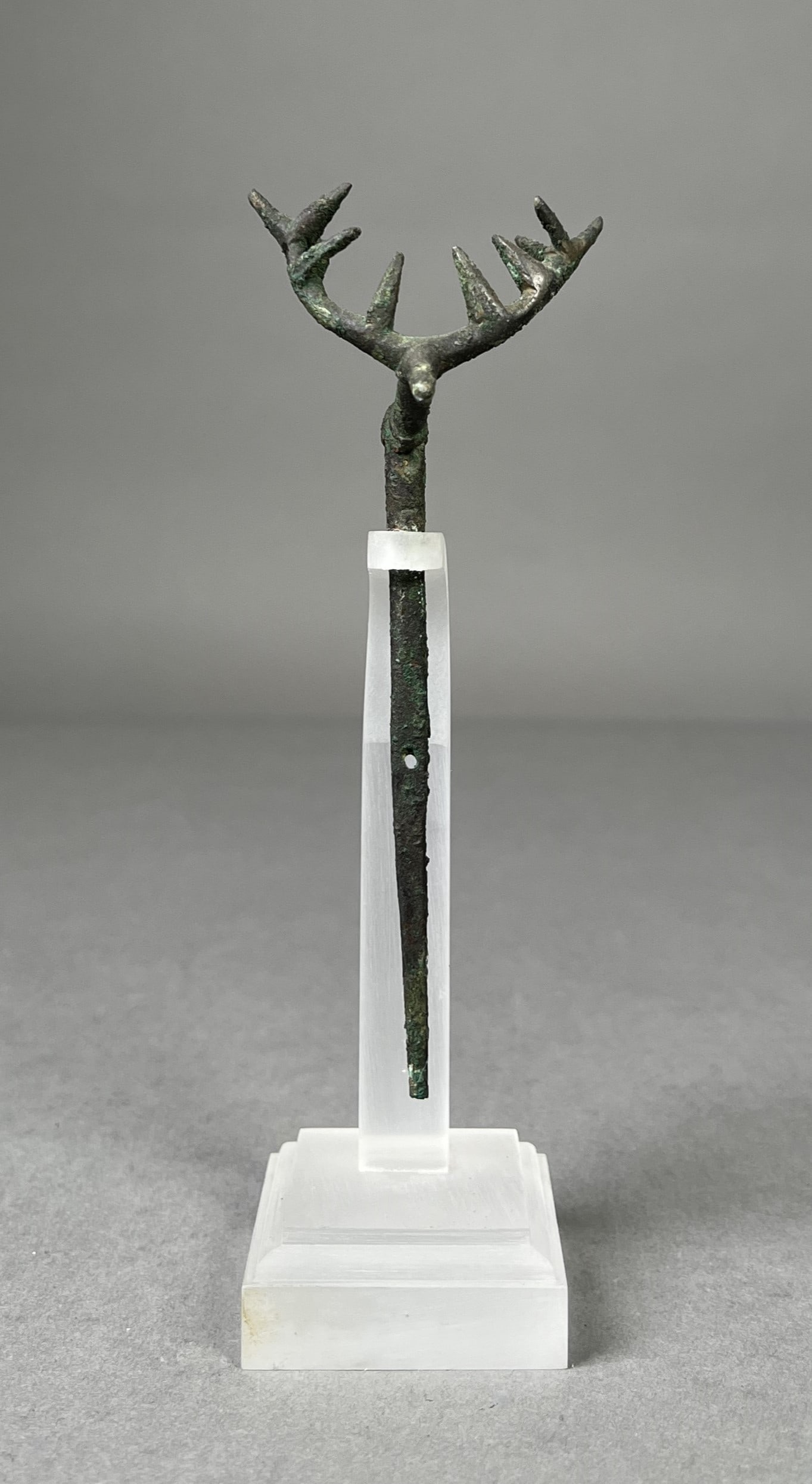 Ancient Bronze Antler-Headed Fibula: This is a bronze pin or fibula, likely originating from Lorestan, featuring an antler-shaped head. The intricately designed head resembles stylized antlers, often symbolic of power, nobility, or conne