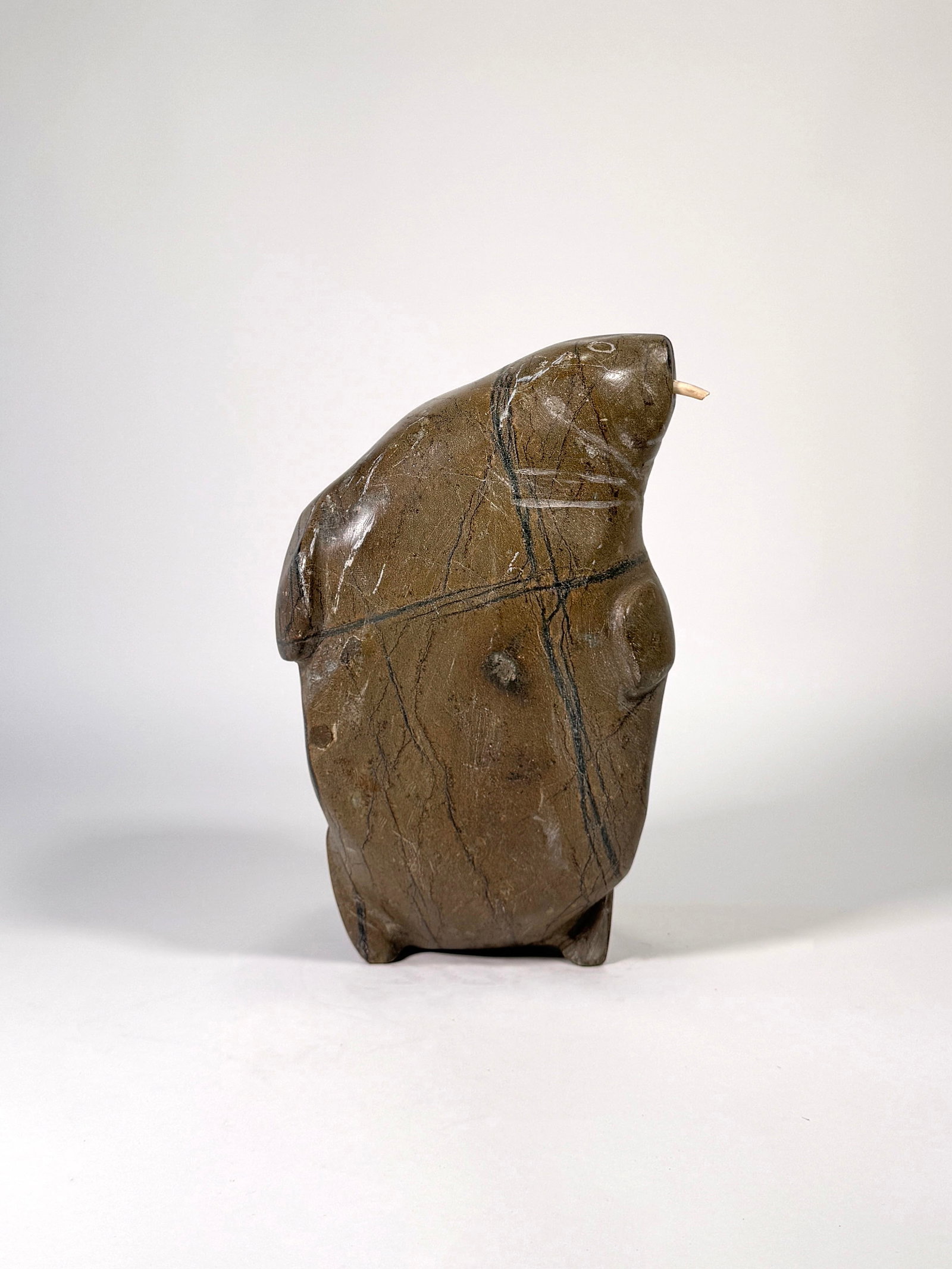 Inuit Carved Walrus: An Inuit carved stone sculpture of a walrus with applied tusk. One tusk is missing. Height: 13" 37.76 oz. 