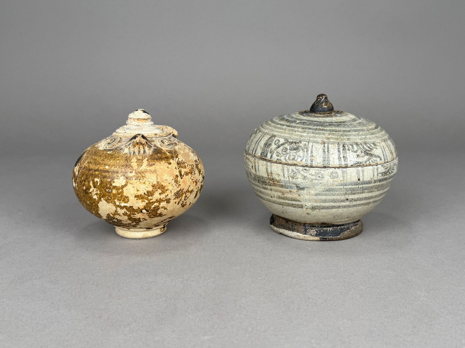 Two Southeast Asian Lidded Vessels: Two lidded ceramic vessels. One earthenware brown glazed lidded vessel that was fired at a high temperature with applied decoration. One Thai Sawankhalok stoneware lidded vessel with blue an