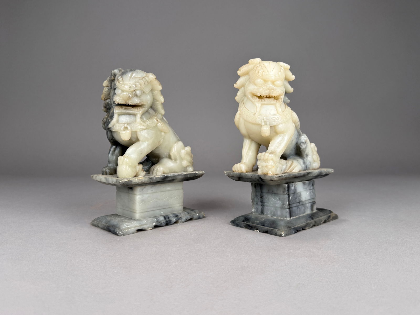 Two Chinese Carved Foo Dog Lions: Two early 20th century carved jade Foo Dog lions, each seated on a carved pedestal. 7.25" x 4.5" (each) 131.1 oz (total weight) . Minor surface wear is present.